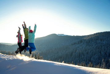 Three young friends jumping and having fun on the snowy mountains