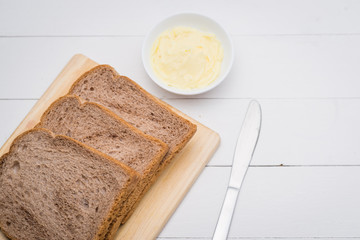 Close-up of slice of toast bread with butter on wood table