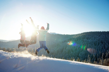 Three young friends jumping and having fun on the snowy mountains