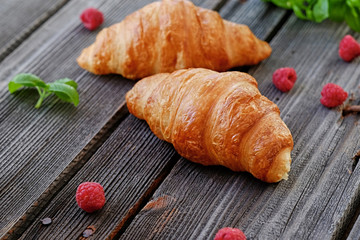 Two croissants on a wooden table.
