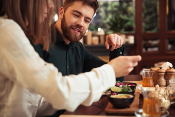 Amazing young loving couple sitting in cafe and eating