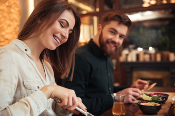 Amazing young loving couple sitting in cafe and eating.