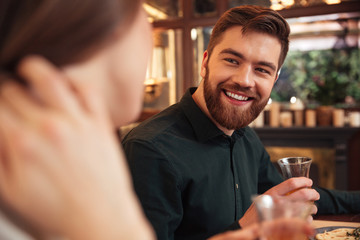 Smiling young loving couple sitting in cafe and eating