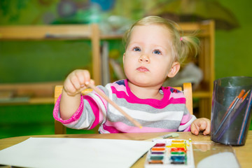 Fototapeta na wymiar Adorable child girl drawing with colorful pencils in nursery room. Kid in kindergarten in Montessori preschool class.
