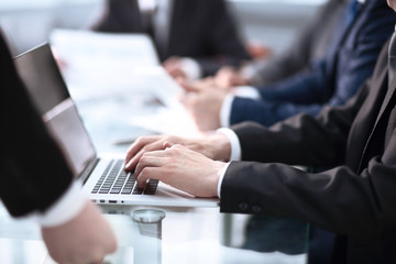 Happy business man working a modern laptop computer with his team in background