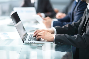 Happy business man working a modern laptop computer with his team in background