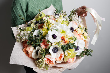 Rich bunch of anemones, poppies, lilacs and white orchid, green leaf in hand Fresh spring bouquet. Summer Background.