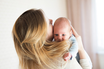 Unrecognizable young mother holding baby son in her arms