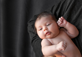  Newborn baby on a black background.  Baby resting in mother's hand. Newborn concept and the concept of a young family
