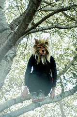 Mujer con máscara de lobo sobre rama de árbol