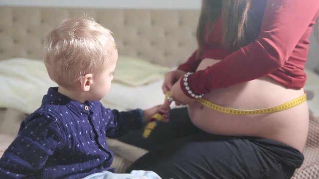 Mummy and her son are measuring a belly. FULL HD - close up