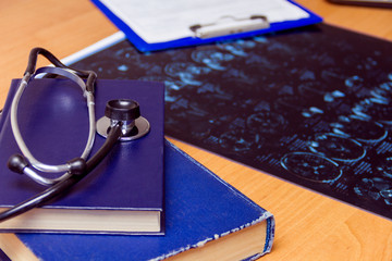 Medical workplace: x-ray image, stethoscope, books isolated on wooden background