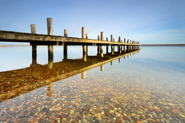 Obraz premium Calm clear lake with wooden pier