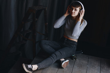 Young girl sitting on skateboard with headphones