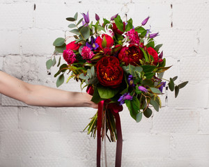 Creative bouquet of flowers at arm's length, beautiful flowers as a gift beloved.