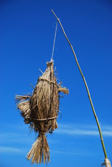 Handmade rice straw fish as festival icon.The fish was hung on a bamboo pole, beautiful blue sky as background.