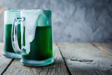Green beer in mugs on rustic wood background