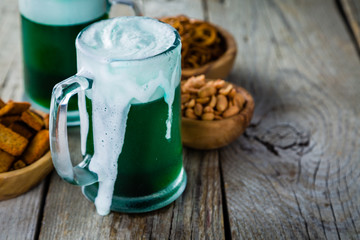 Green beer in mugs on rustic wood background
