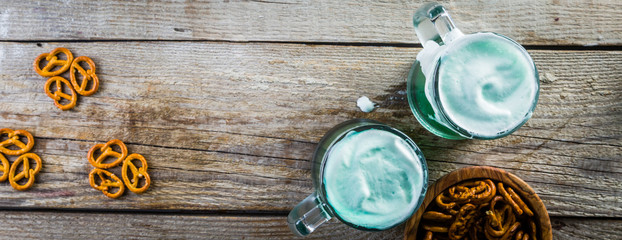 Green beer in mugs on rustic wood background