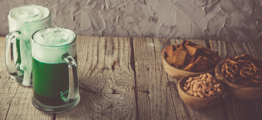 Green beer in mugs on rustic wood background