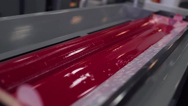 Printing press, red paint mixing shaft, printing production. 4k footage.
