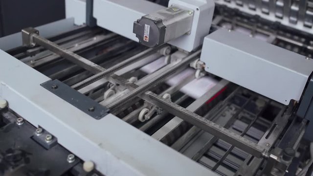 Offset printing press, industrial machine moving the paper material. Print house. Close-up. 4k footage.
