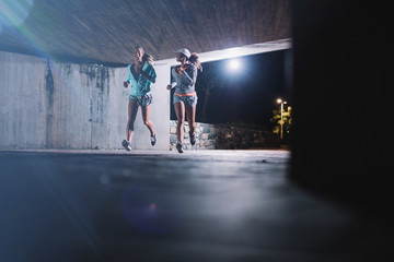 Two young women jogging at night in city