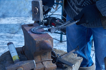 blacksmith forges horseshoe on anvil