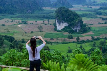 Woman taking photo with smartphone at mountain, beautiful view from Thailand.