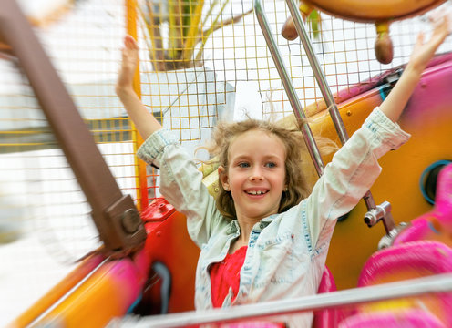 Happy little girl having fun in amusement park.