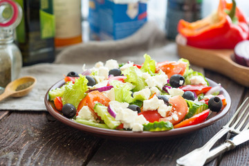 Homemade Greek Salad with Fresh Vegetables, Feta Cheese and Black Olives on Dark Wooden Table, Horizontal Close Up View