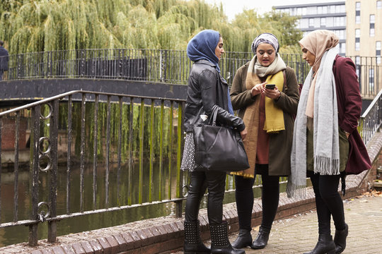 Muslim Female Friends Using Mobile Phone In Urban Setting