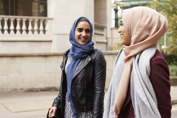 British Muslim Female Friends Walking In Urban Environment