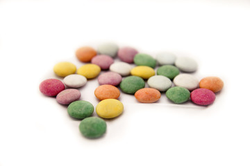 Colored candy. Multicolored colorful candy with white background closeup. Colorful chocolate button candies spread randomly on white background. Background image of sweet candies or chocolate buttons.
