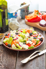 Greek Salad with Fresh Vegetables, Feta Cheese and Black Olives on Dark Wooden Table