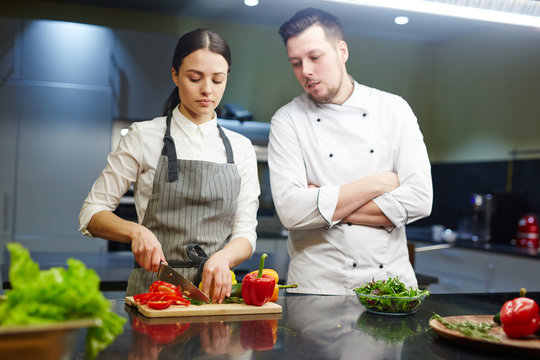Professional chef and his trainee cooking fresh vegetable salad