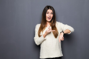 Portrait of positive pretty young woman pointing at clock