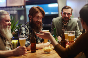 Friendly guys with beer spending evening in pub