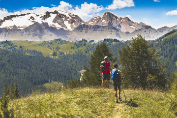 Fototapeta na wymiar Hikers in beautiful landscape of Dolomites Italy - Hiking in the mountains. Pair of hickers with bacpack