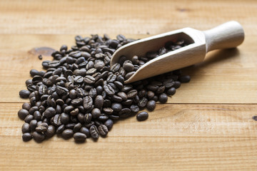 coffee beans with wooden scoop on wooden background