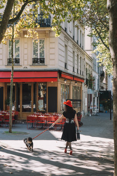 Dame au chapeau rouge avec son chien dans la rue