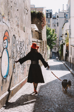 Dame au chapeau rouge avec son chien dans la rue