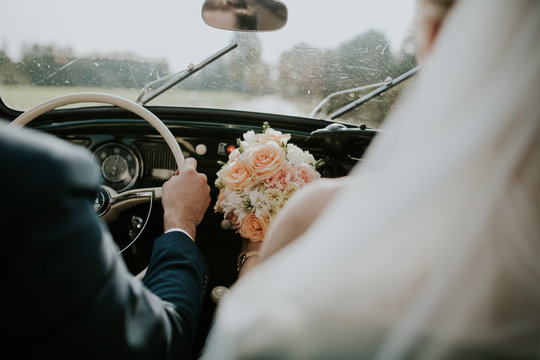 Bride and groom driving car 