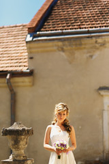 Gorgeous thoughtful bride stands by ruined old vase outside