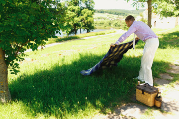 Man in violet shirt lies violet plaid on green lawn