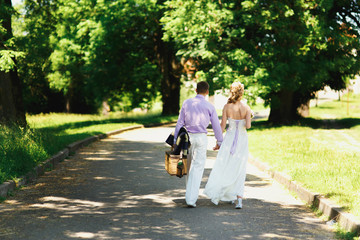 Look from behind at groom in violet shirt and bride walking with a basket