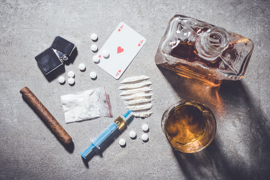 Overhead shot of hard drugs and alcohol on gray stone background