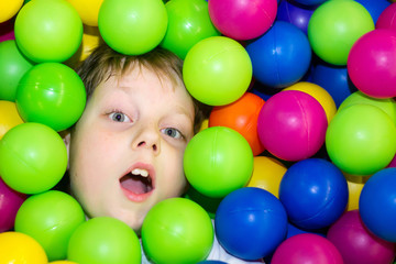 Fototapeta na wymiar Boy lying in a pile of colored balls