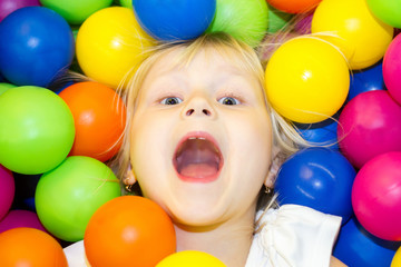 Fototapeta na wymiar little girl lying in a pile of colored balls