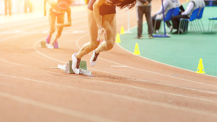 Sportswomen starting running sprint from starting blocks